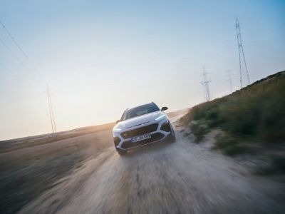 Nový Hyundai KONA N vo farbe Sonic Blue jazdiaci po štrkovej ceste, demonštrujúci nápravu N Power Sense Axle.