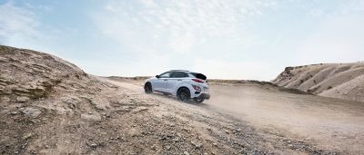 Nový Hyundai KONA N vo farbe Sonic Blue jazdiaci do kopca po štrkovej ceste.