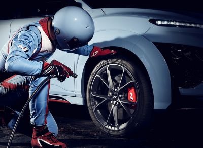 Muž v kombinéze N kontrolujúci pneumatiky Pirelli P Zero nového modelu Hyundai KONA N.